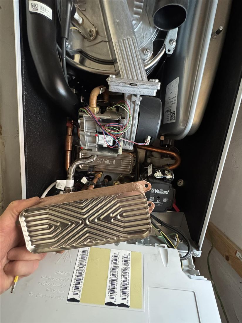 Plate heat exchanger held up beside an open boiler