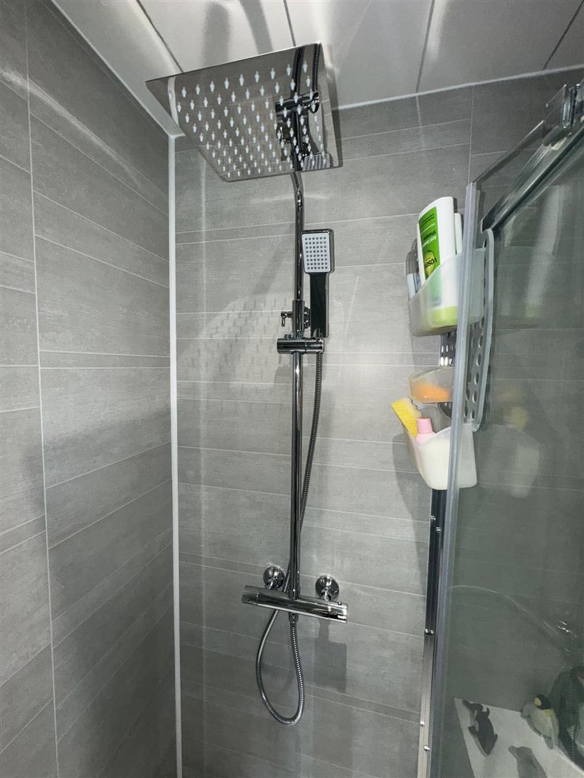 New thermostatic shower with a rain head on grey tiles